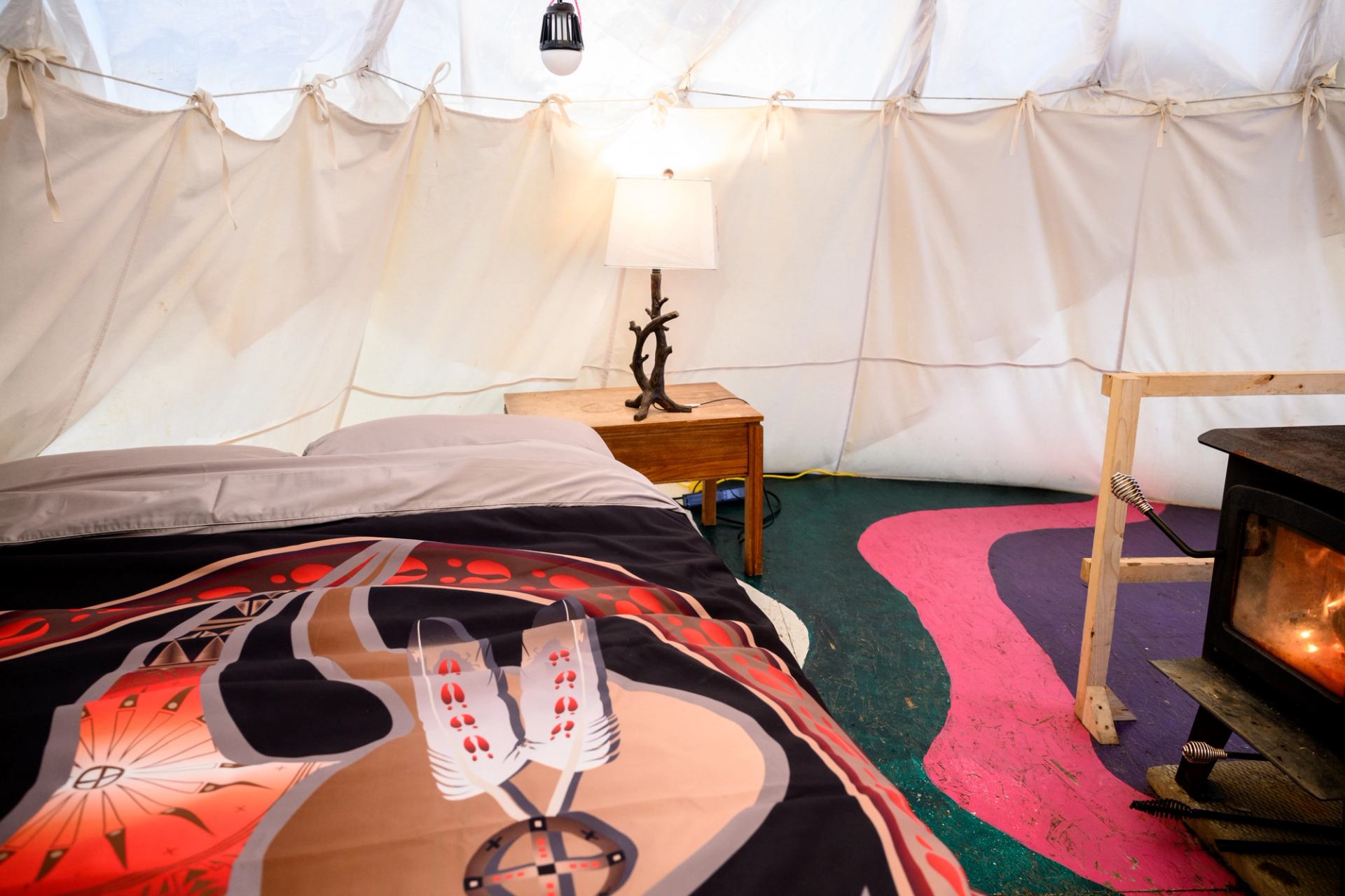 Isde a 18ft teepee bed with indigenous duvet cover, fire burning, floor painted in aurora designs