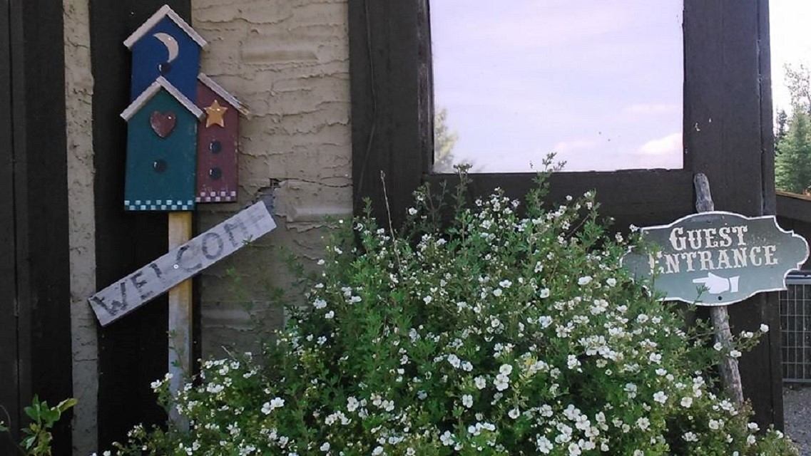 Colorful welcome signs and blooming flowers near the guest entrance of the lodge