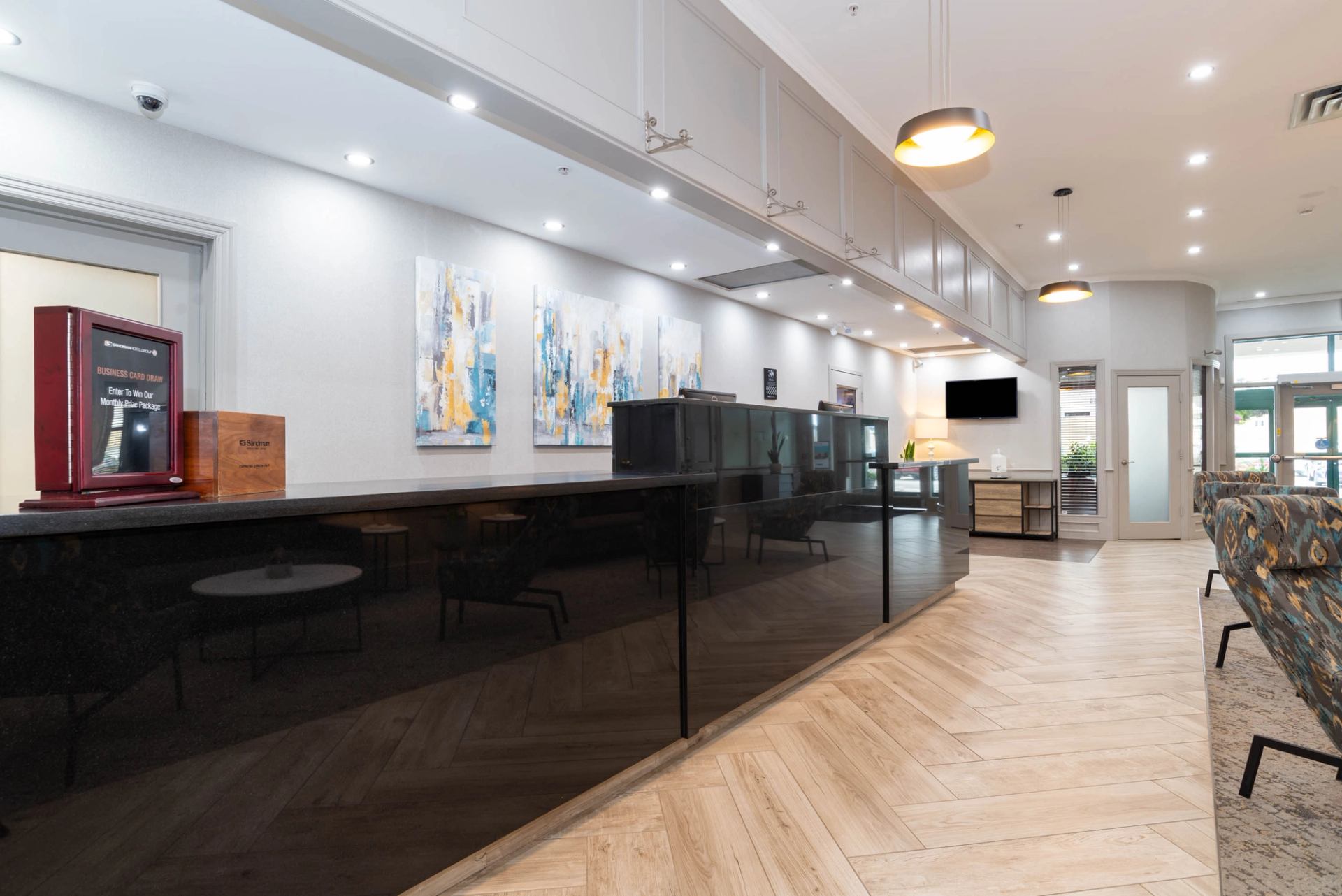 Hotel lobby reception desk with black counter, abstract wall art and seating area.