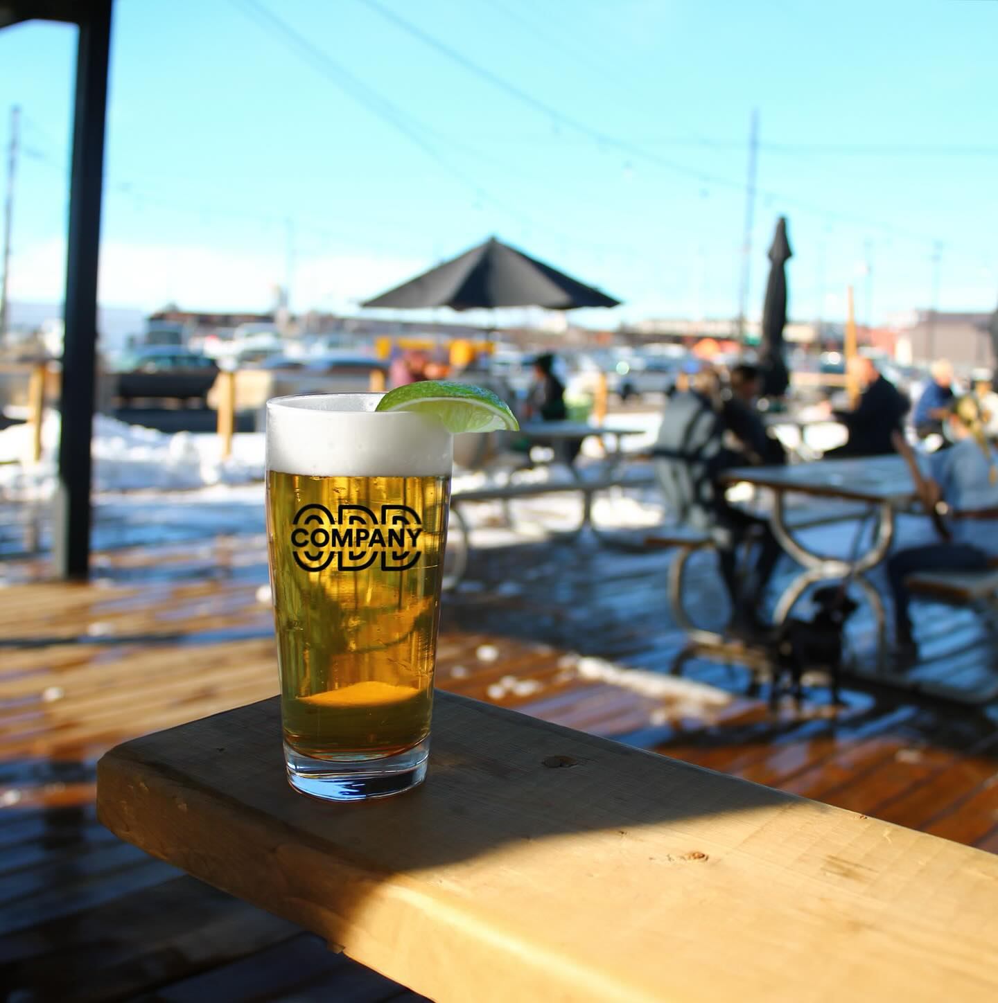 Pint of beer with lime wedge on an outdoor patio deck in sunny weather