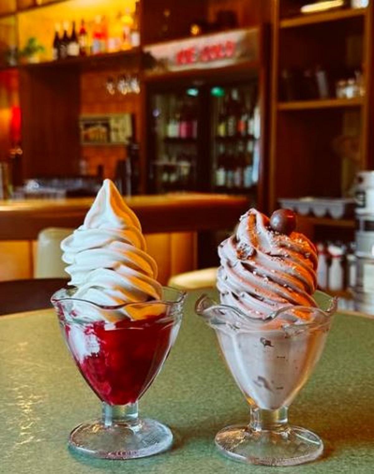 Two sundaes in vintage dishes sat on the table. One chocolate and one cherry.