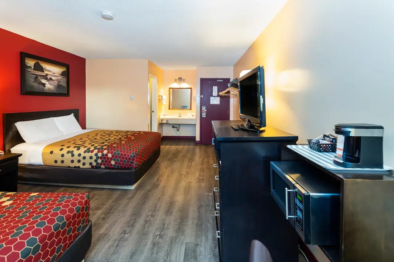 Hotel room with two beds, television, microwave, coffee maker and open vanity.