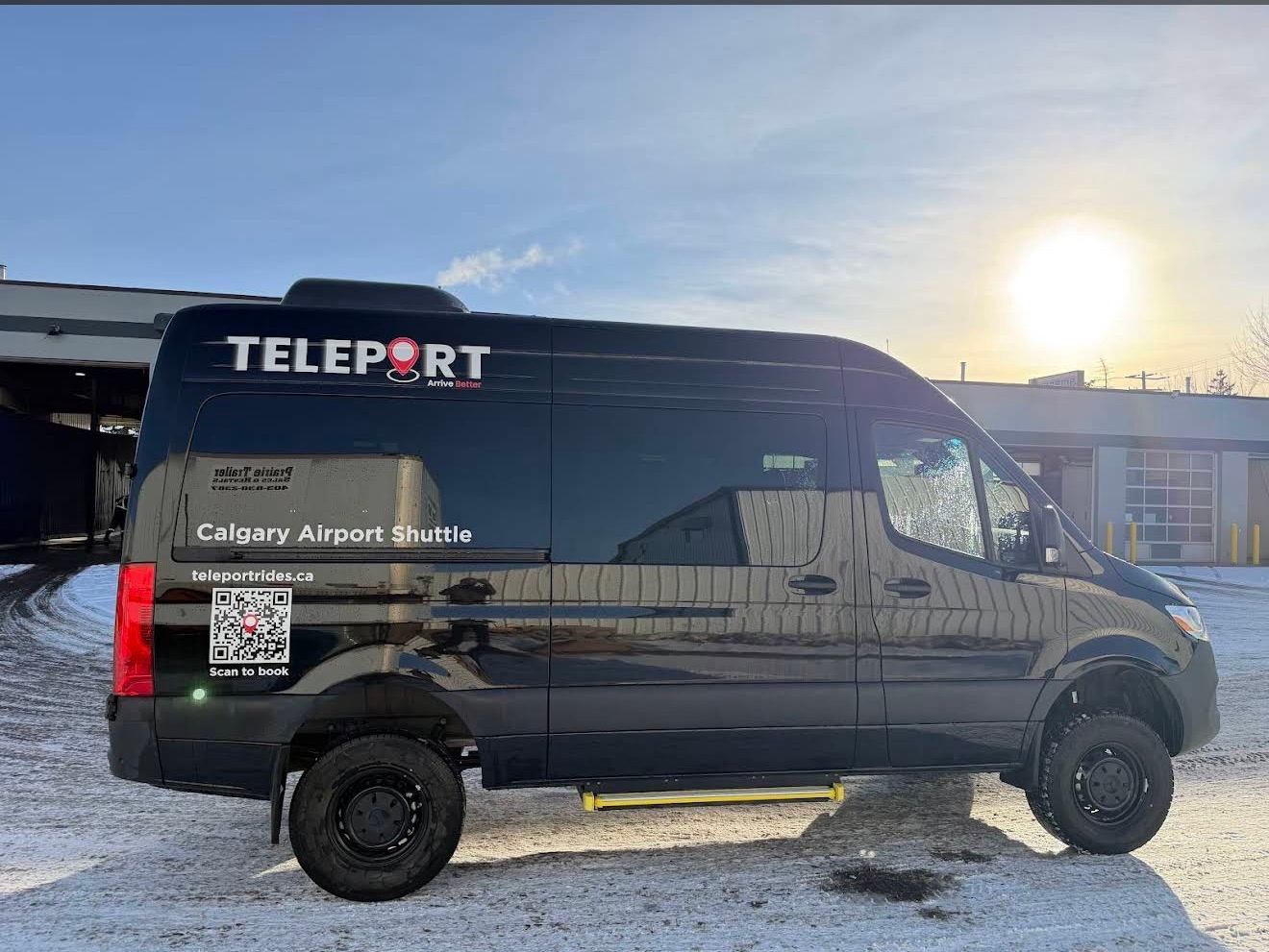 Black Teleport Calgary Airport Shuttle van parked on snowy lot beside industrial buildings.