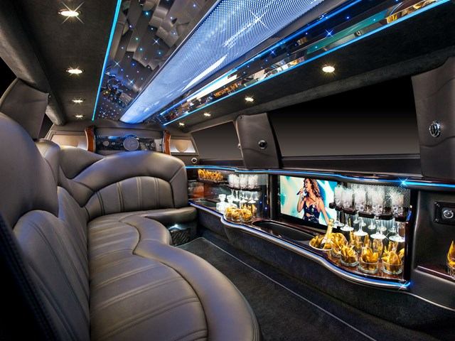 Luxurious Quest Limos interior with leather seats, ambient lighting, bar area, and screen.