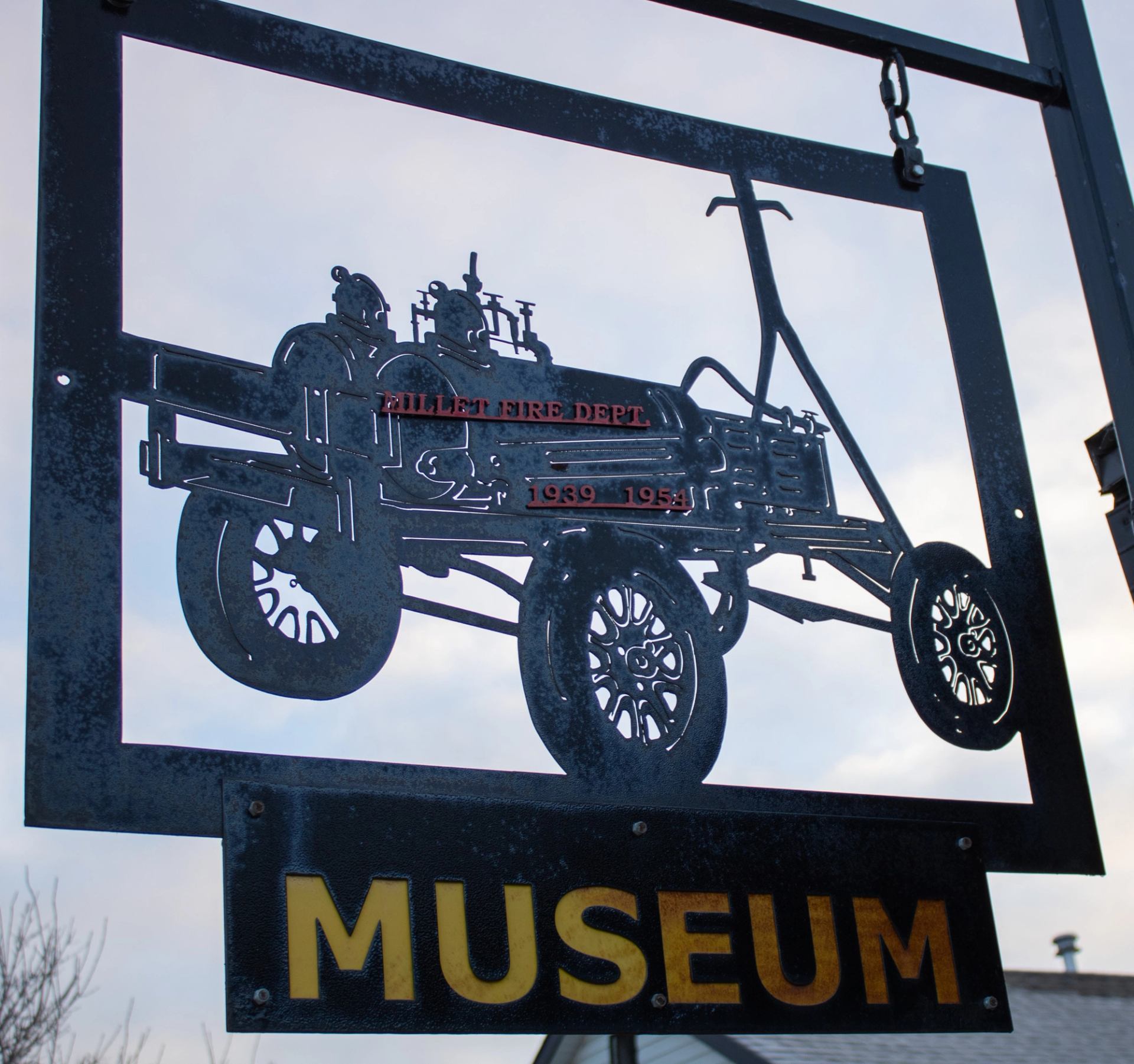 Metal museum sign featuring an old fire wagon silhouette with bold “MUSEUM” text below.