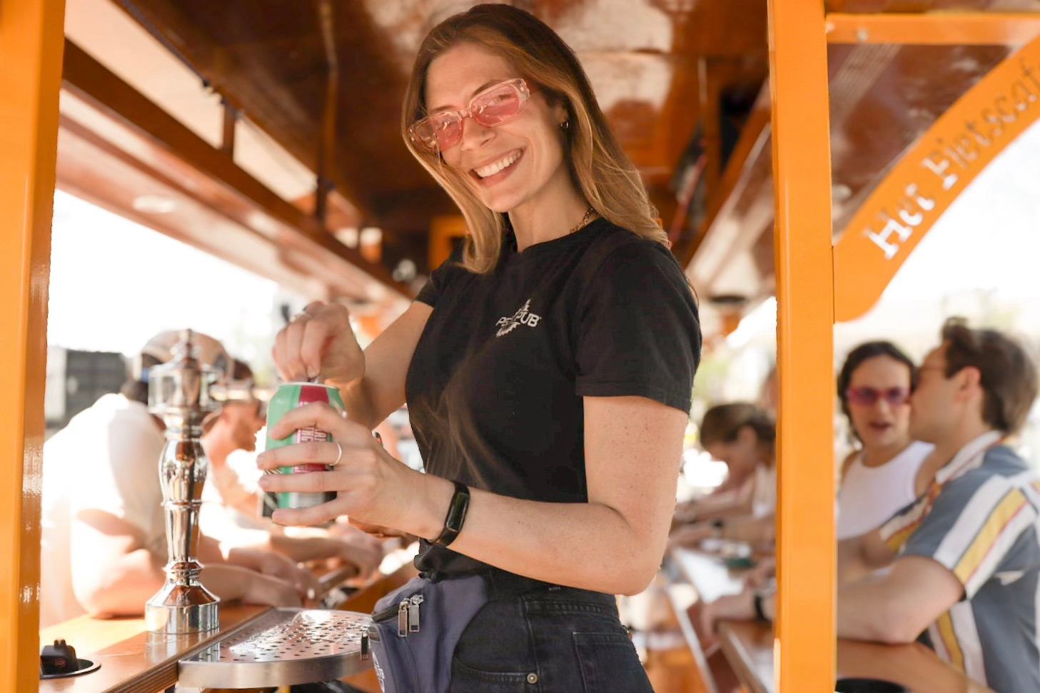 Bartender serving a drink inside a Pedal Pub bike while guests ride and socialize in Edmonton.