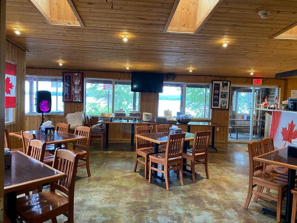 Cozy dining area with wooden tables, chairs, and Canadian flags inside Christina Lake Lodge.
