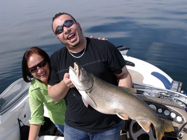 Two anglers on a boat proudly holding a large catch.