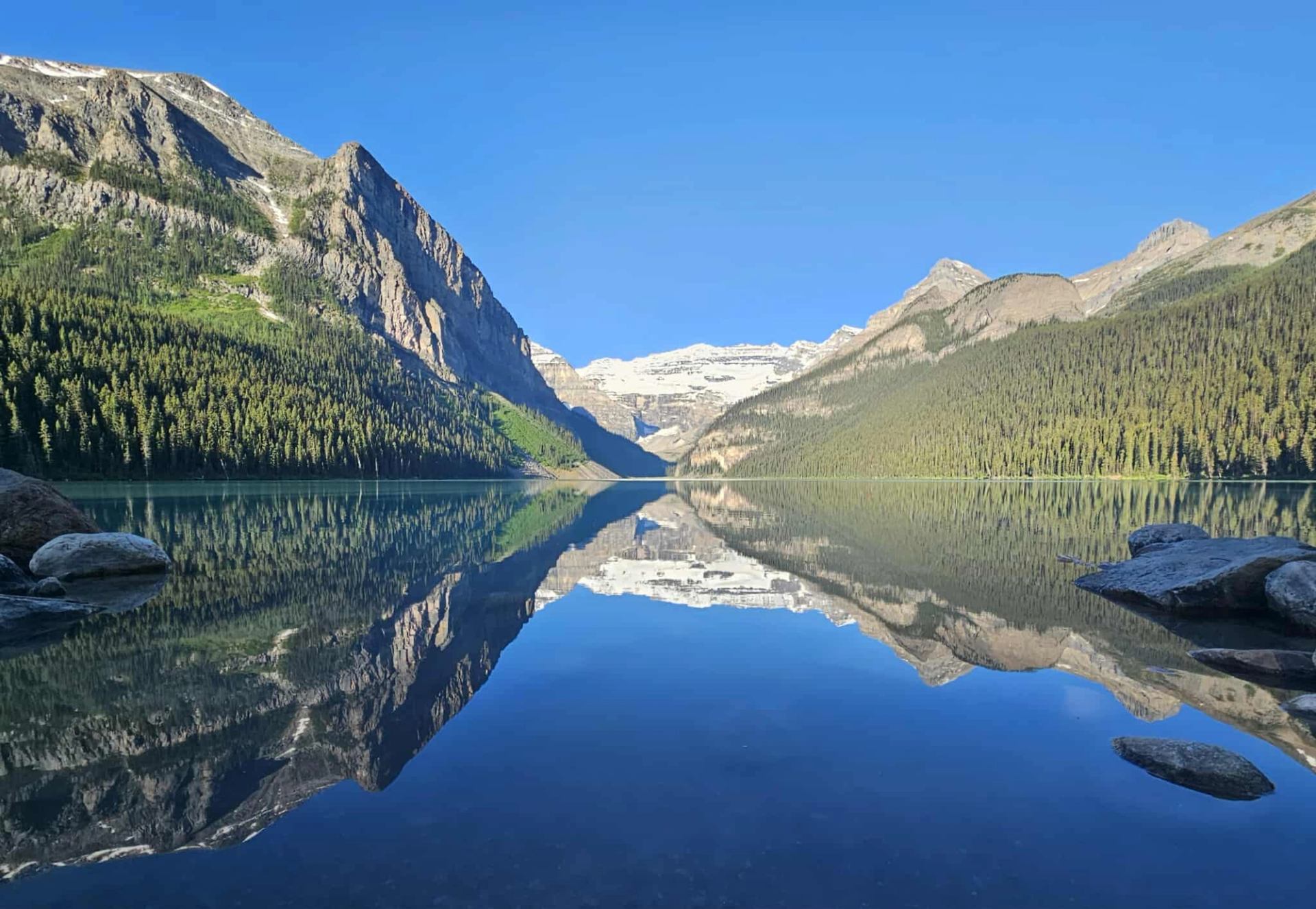 Clear mirror-like reflection of Lake Louise and surrounding peaks.