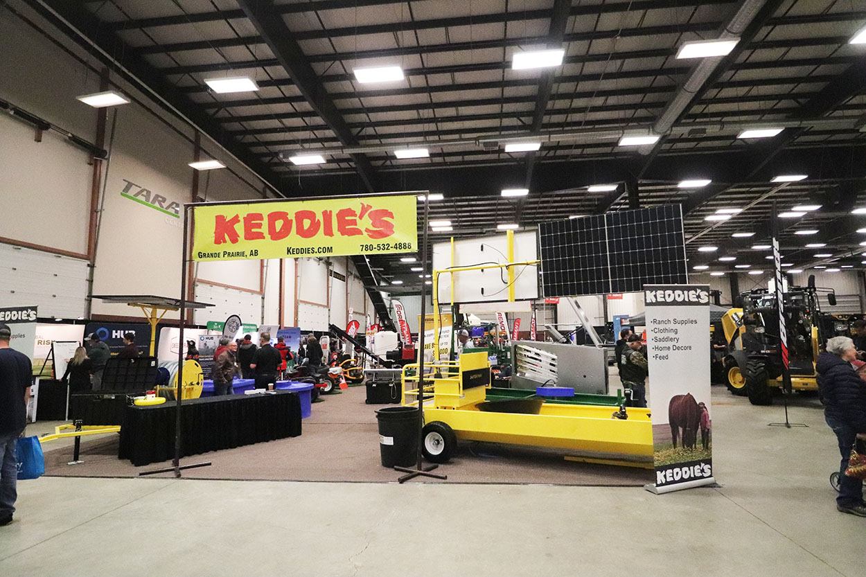 Indoor agri‑show with booths, machinery, and visitors walking through