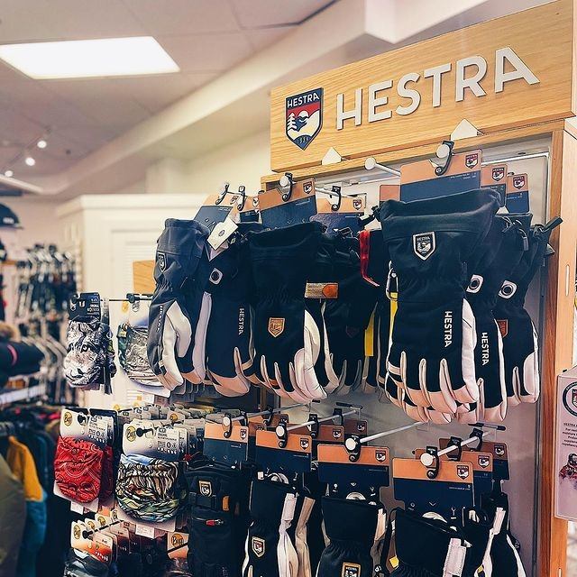 Display of HESTRA gloves in various styles and colors at a retail store.