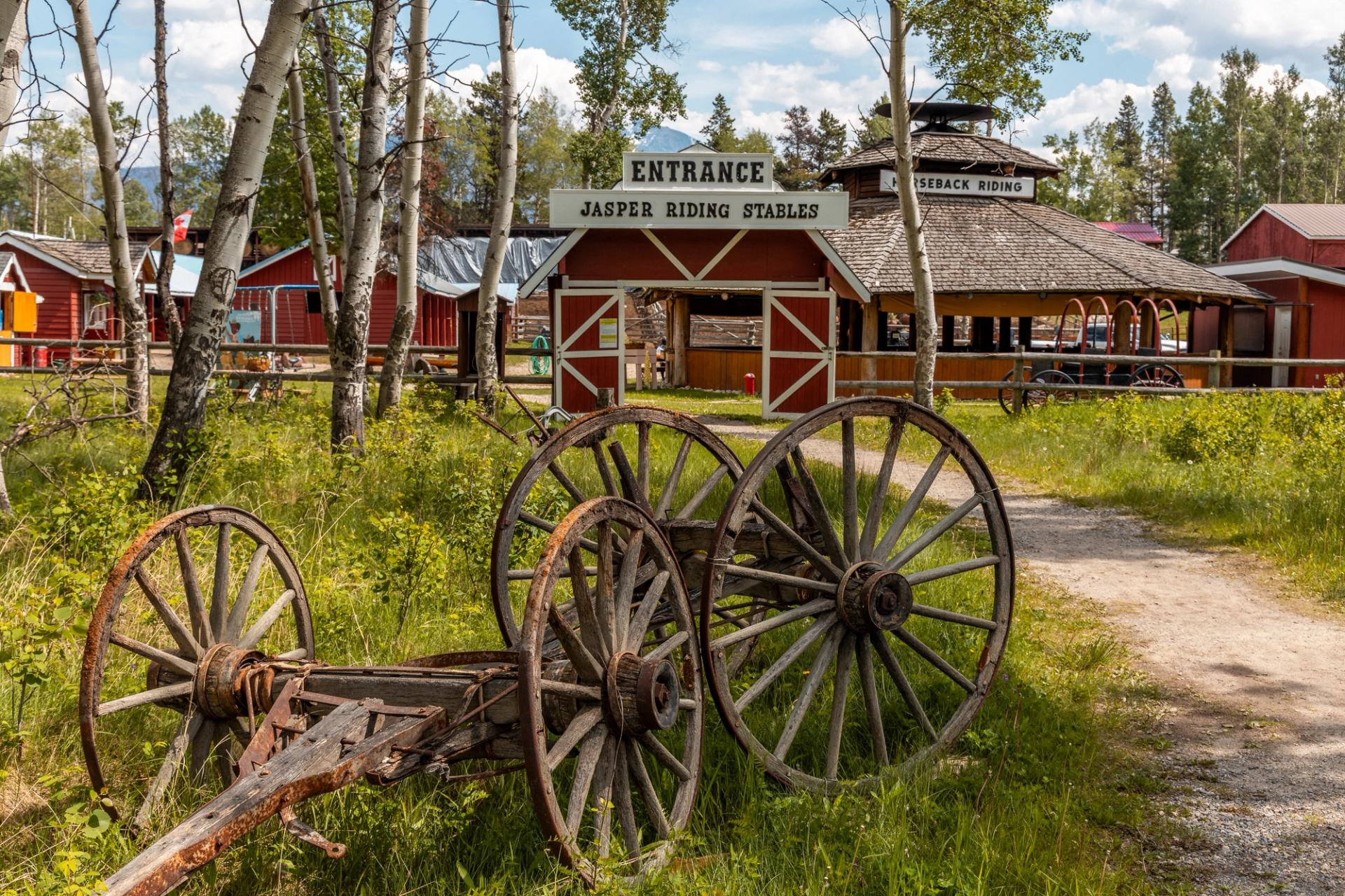 Entrance to Jasper Riding Stables with wooden sign and wagon wheels.