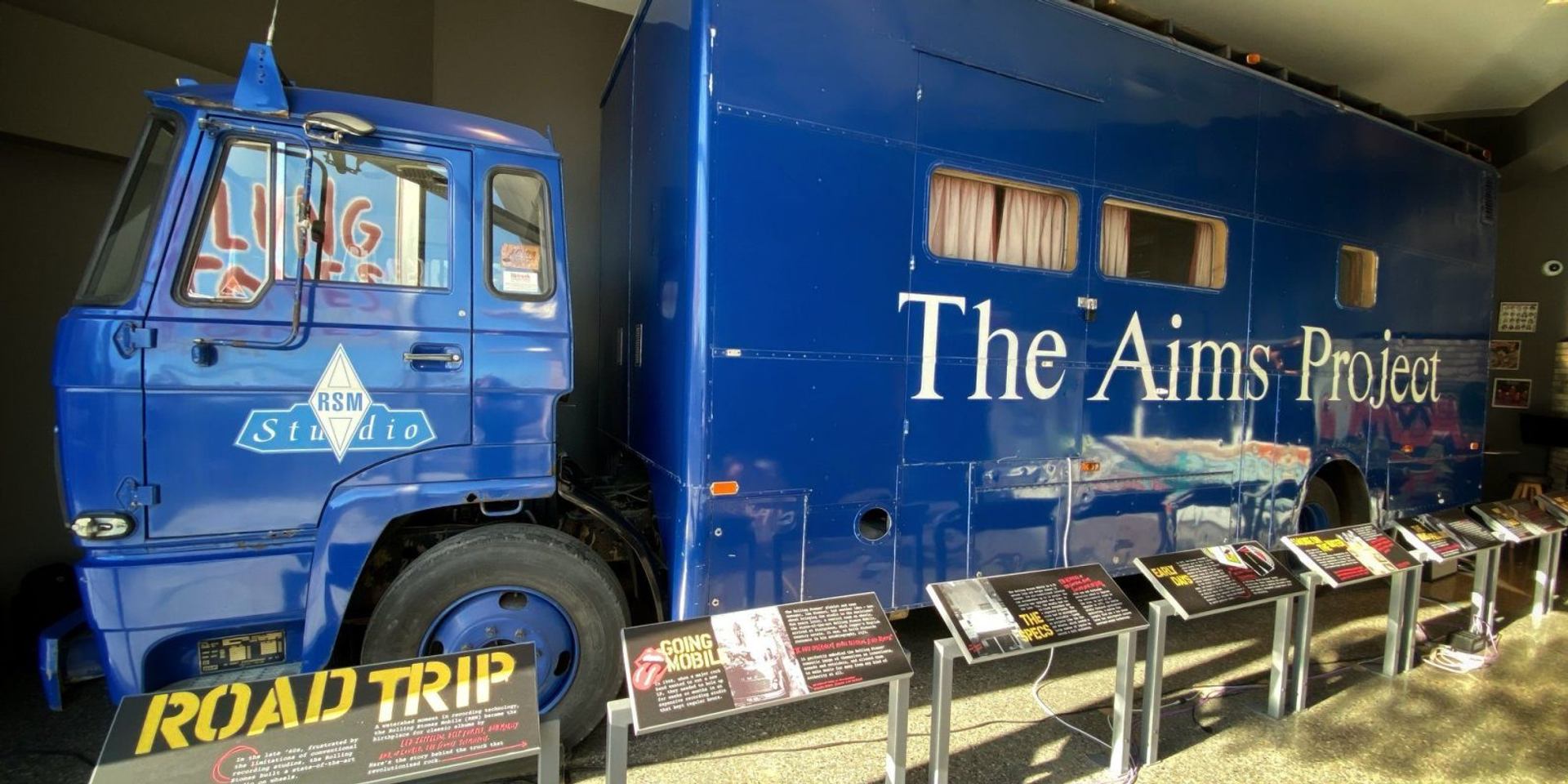 Blue RSM Studio truck labelled The Aims Project displayed with informational museum panels.