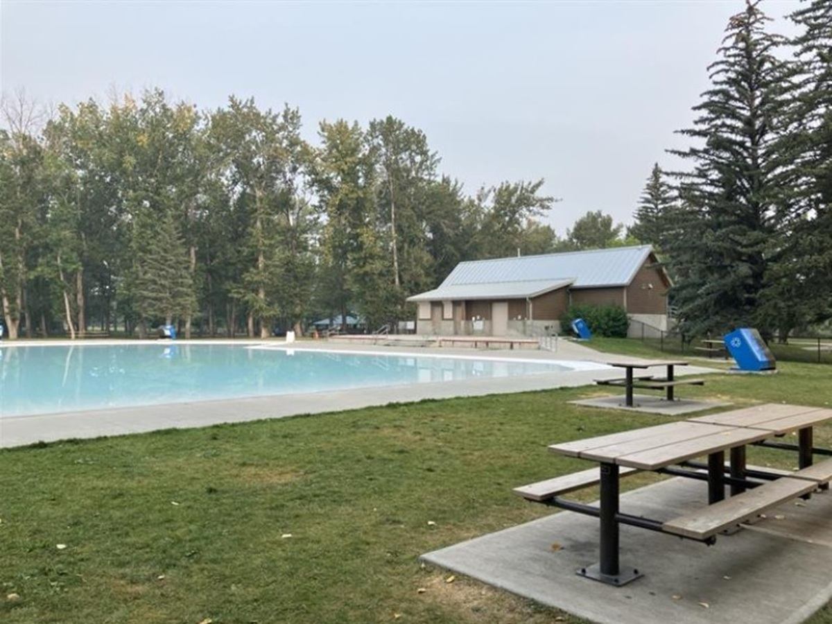 Tranquil pool with picnic tables and building at Bowness Park