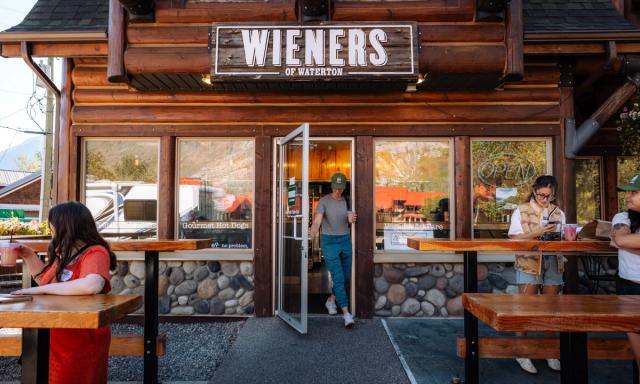 Woman walking out of Wieners of Waterton with a drink.