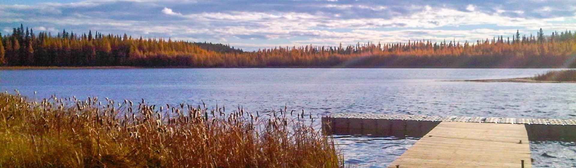 Wooden dock extending into a calm lake surrounded by autumn trees at Machesis Lake Campground.