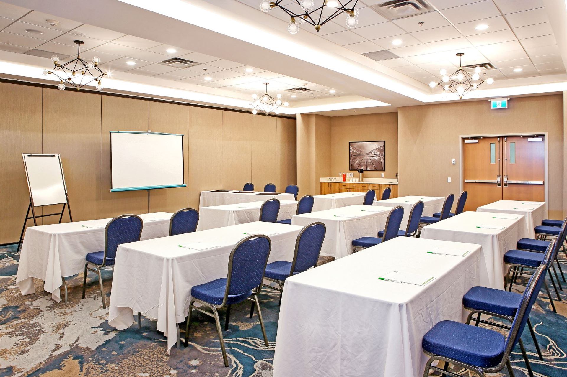Conference room with rows of tables, chairs, and presentation screen