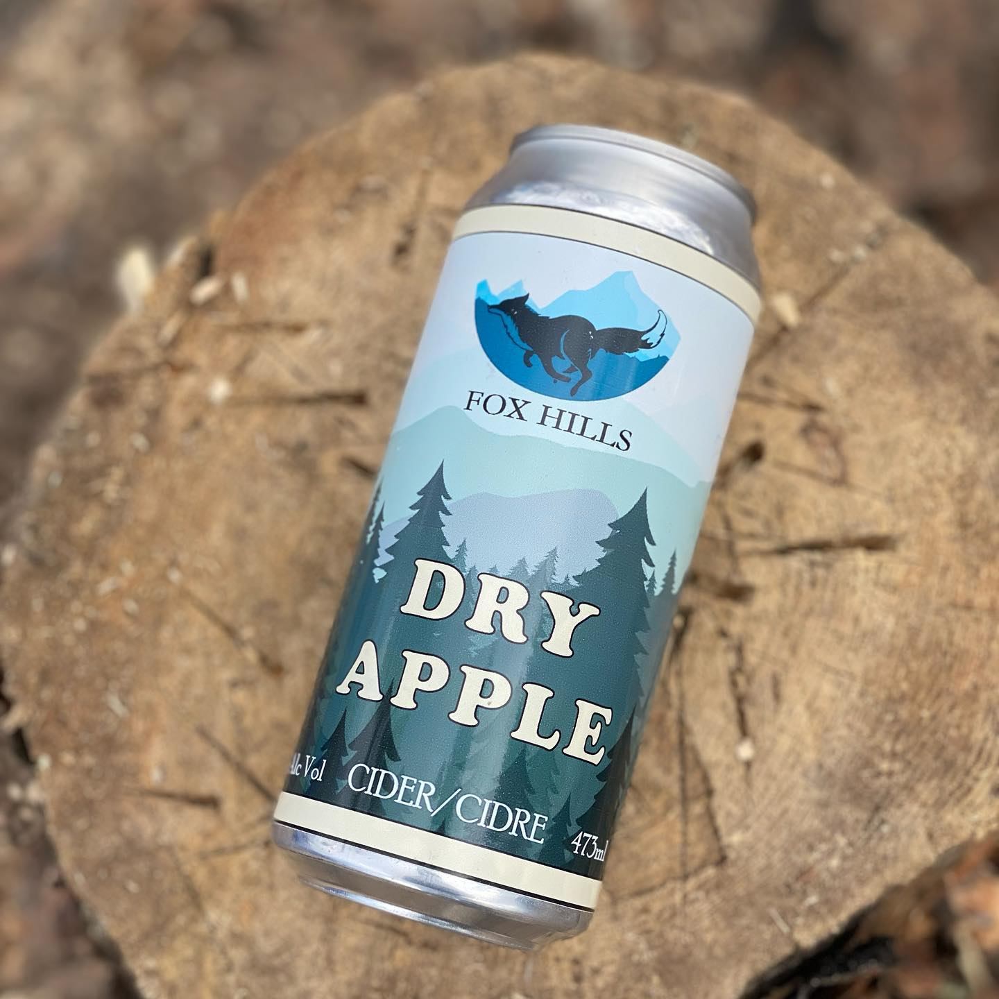 A can of Dry Apple cider on a tree stump.
