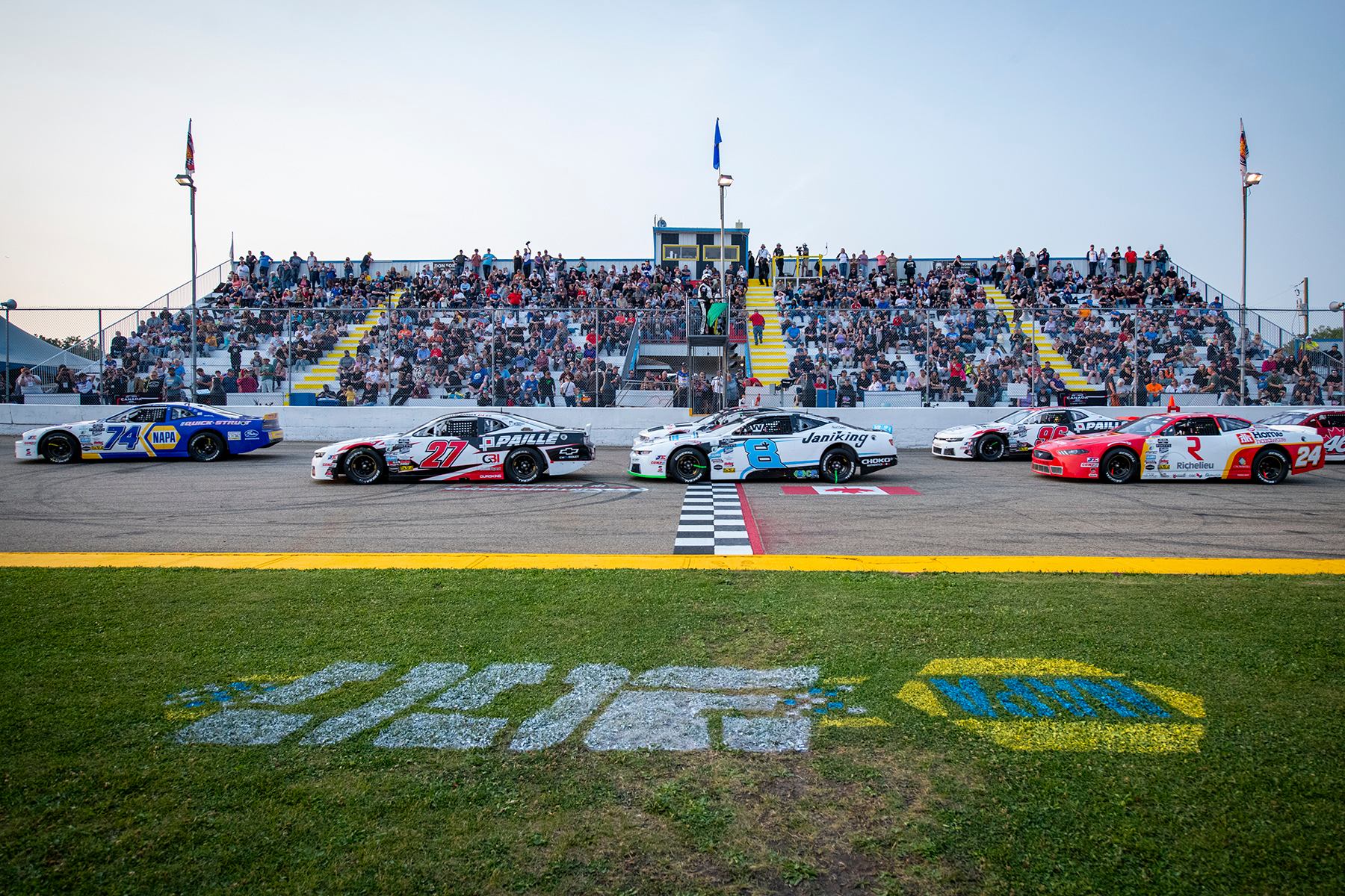 NASCAR Canada NAPA 300 cars lined up at the start line with full grandstands in the background.