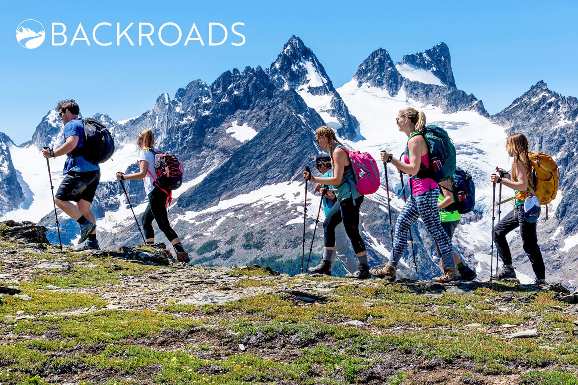 Group hiking through scenic mountains under a clear blue sky.