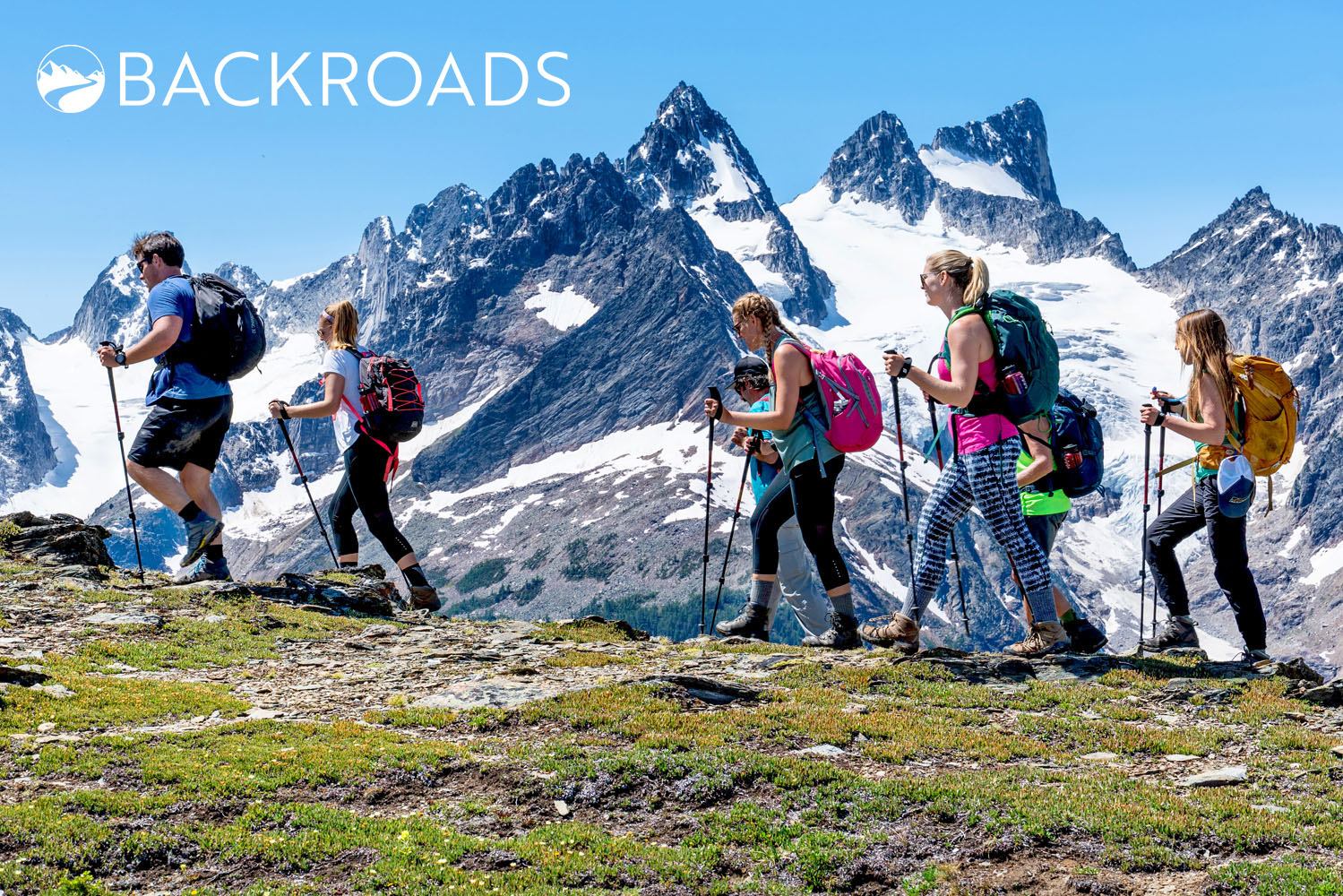 Group hiking through scenic mountains under a clear blue sky.