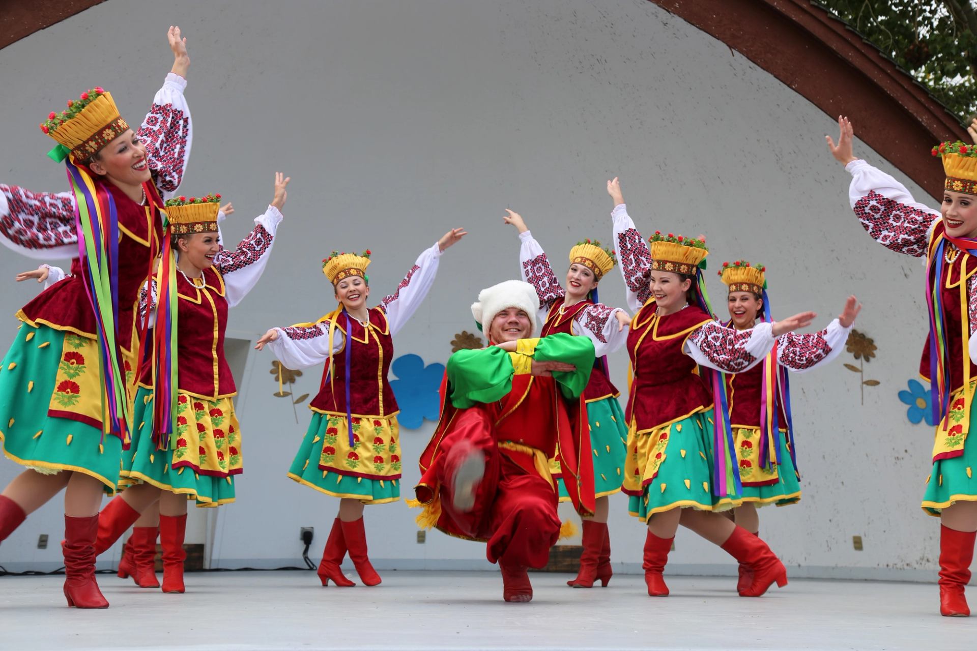 Ukrainian folk dancers in colorful traditional costumes perform a lively routine on an outdoor stage.