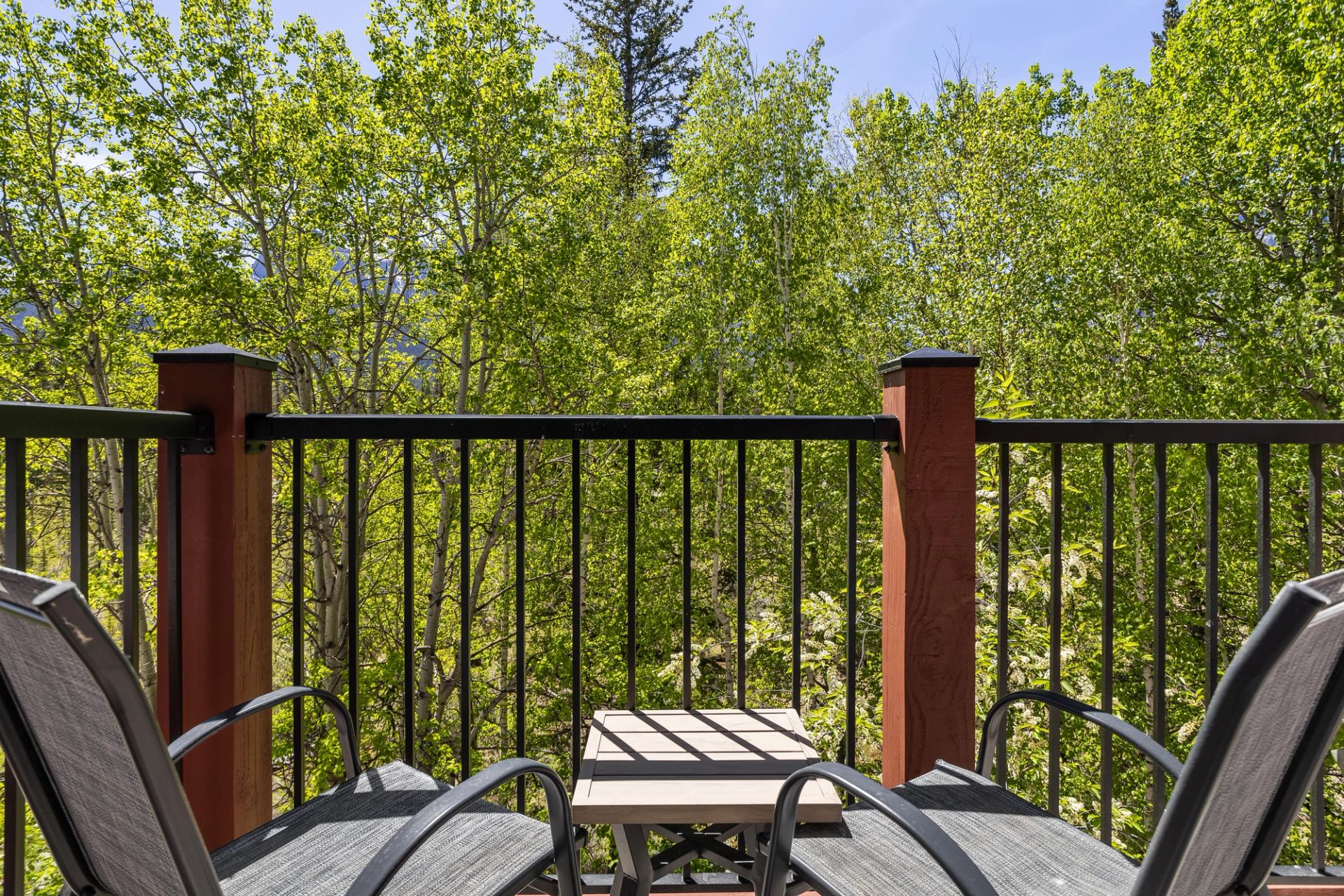 Balcony with two chairs and a small table facing vibrant green forest views.