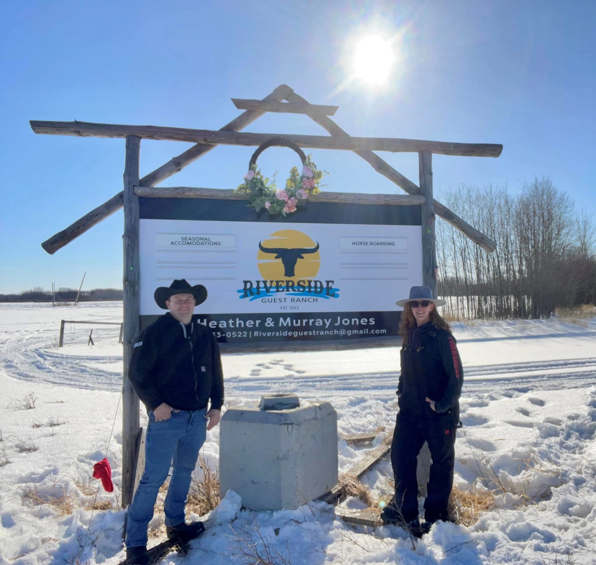 Ranch entrance sign with snow-covered ground and clear sky