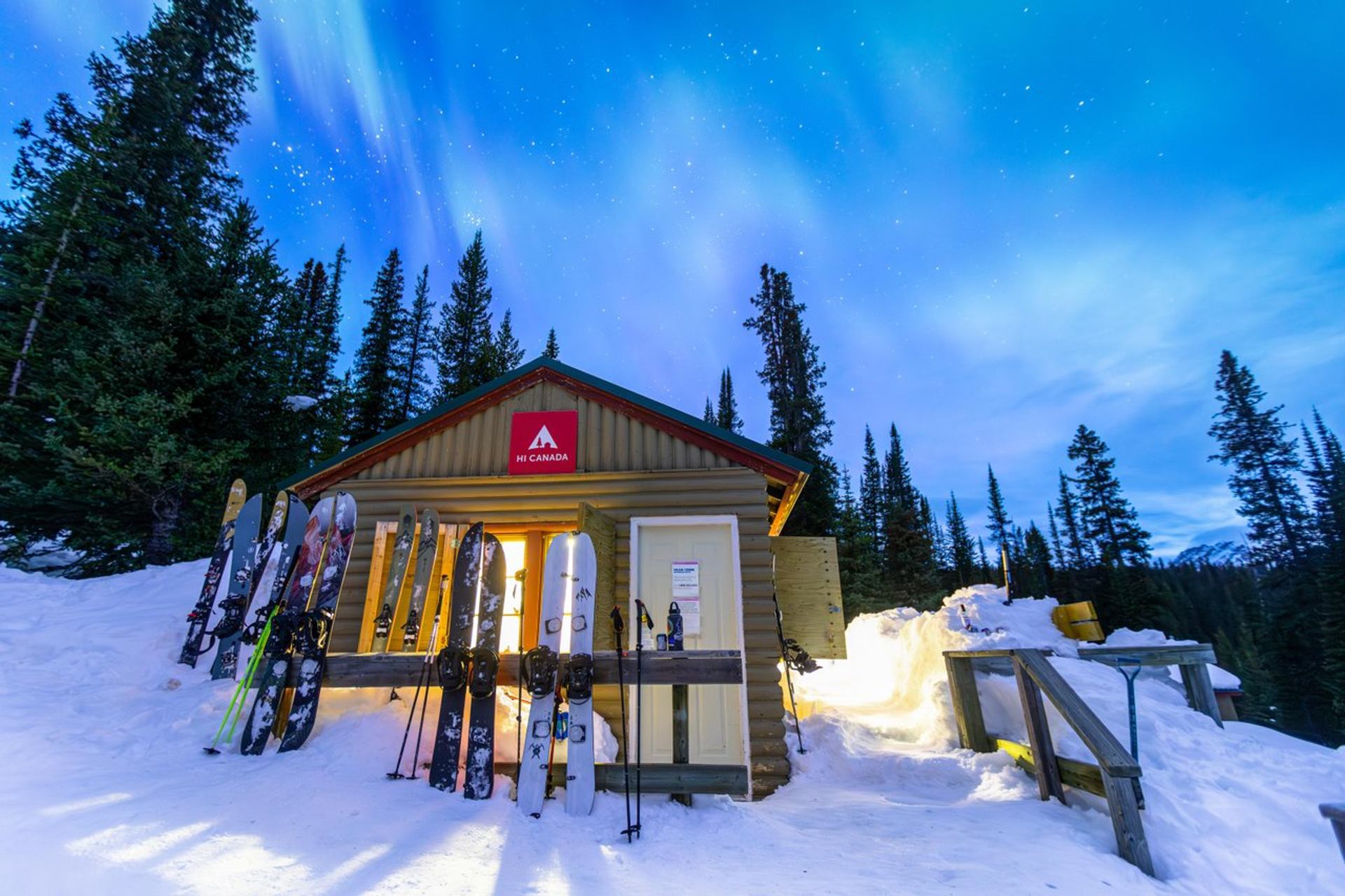 Winter entrance with skis and snowboards propped outside, glowing warm light from the moon.