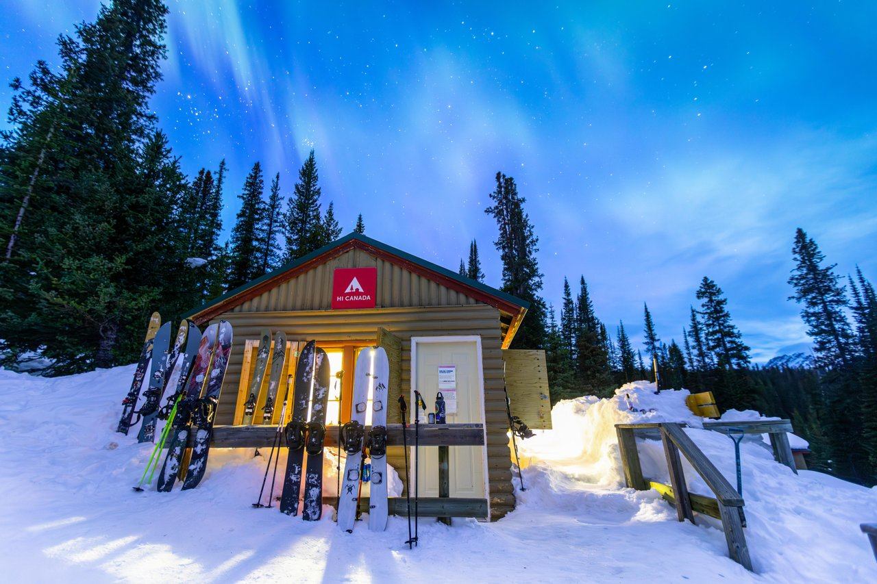 Winter entrance with skis and snowboards propped outside, glowing warm light from the moon.