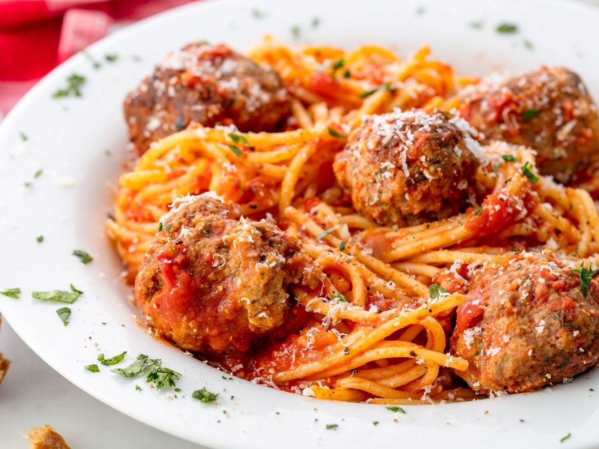 Plate of spaghetti with meatballs, tomato sauce, and grated cheese.
