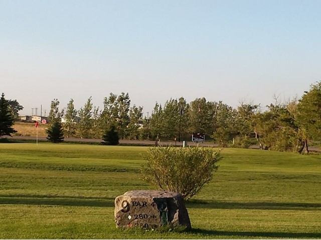 Open fairway at Enchant Golf Club with a distance marker stone.