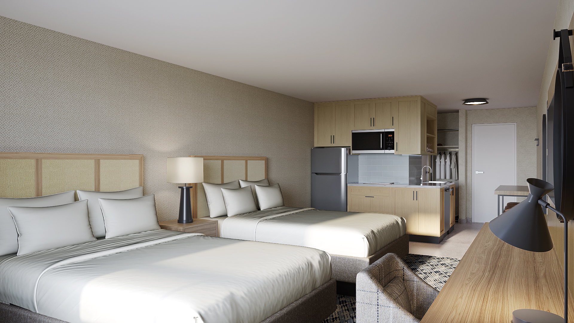 Hotel room with two beds, kitchenette, desk, chair and wall-mounted television.