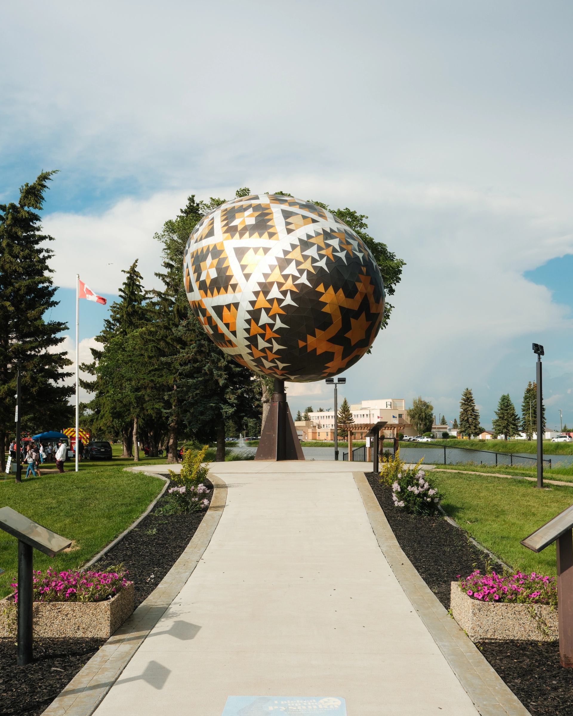 Giant decorated egg sculpture at Vegreville Visitor Centre with flag and flowers.