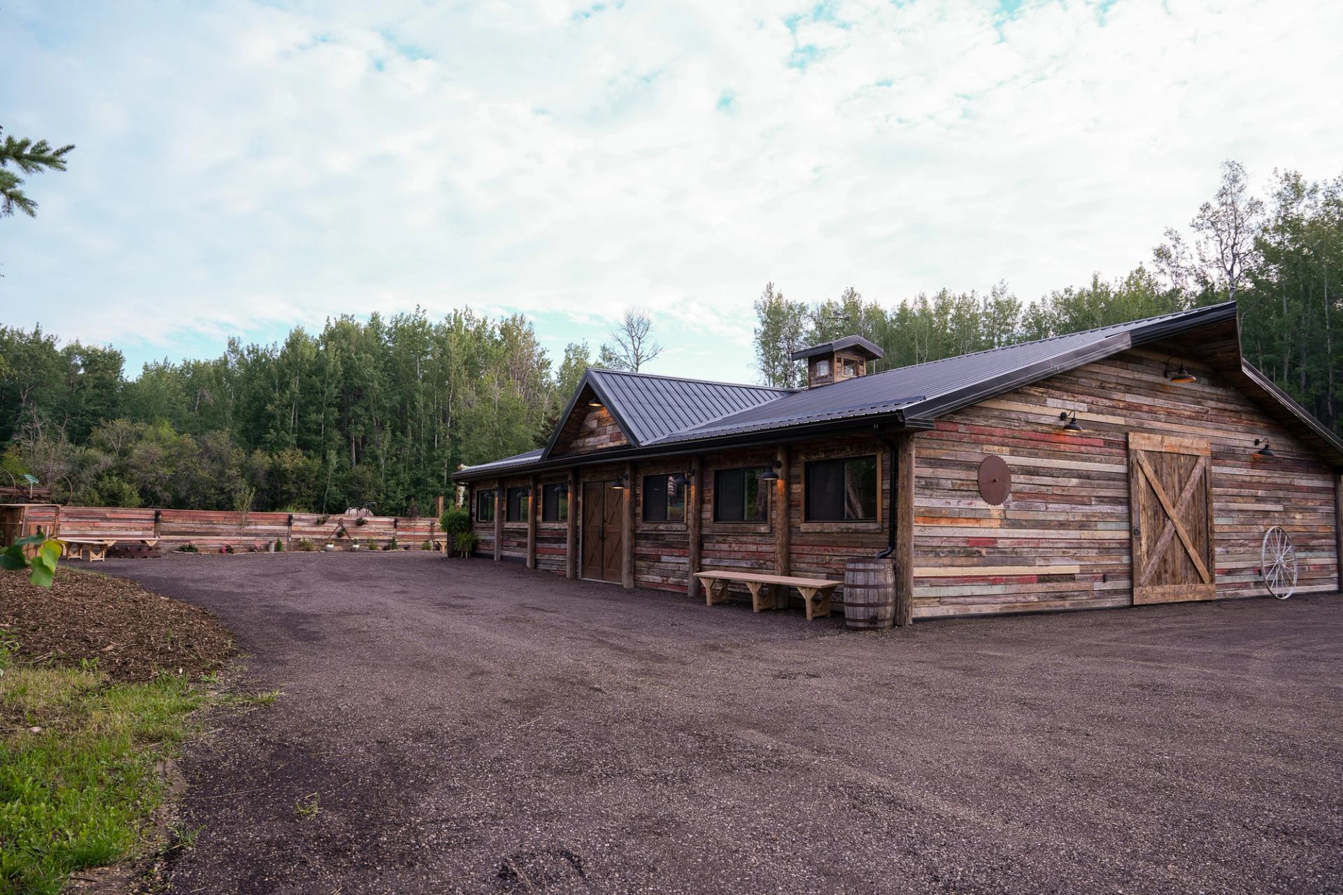 Rustic barn with metal roof in a peaceful, tree-lined rural setting.
