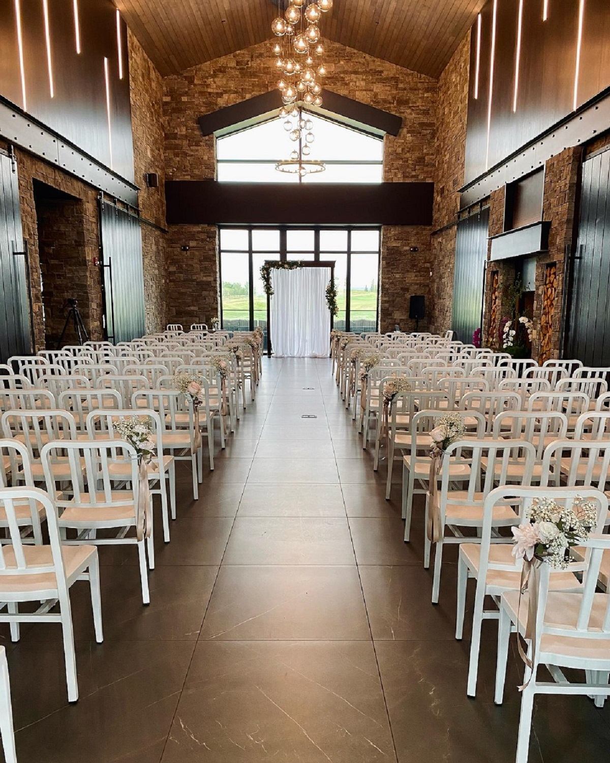 Elegant indoor wedding setup at Mickelson National Golf Club with rows of white chairs.