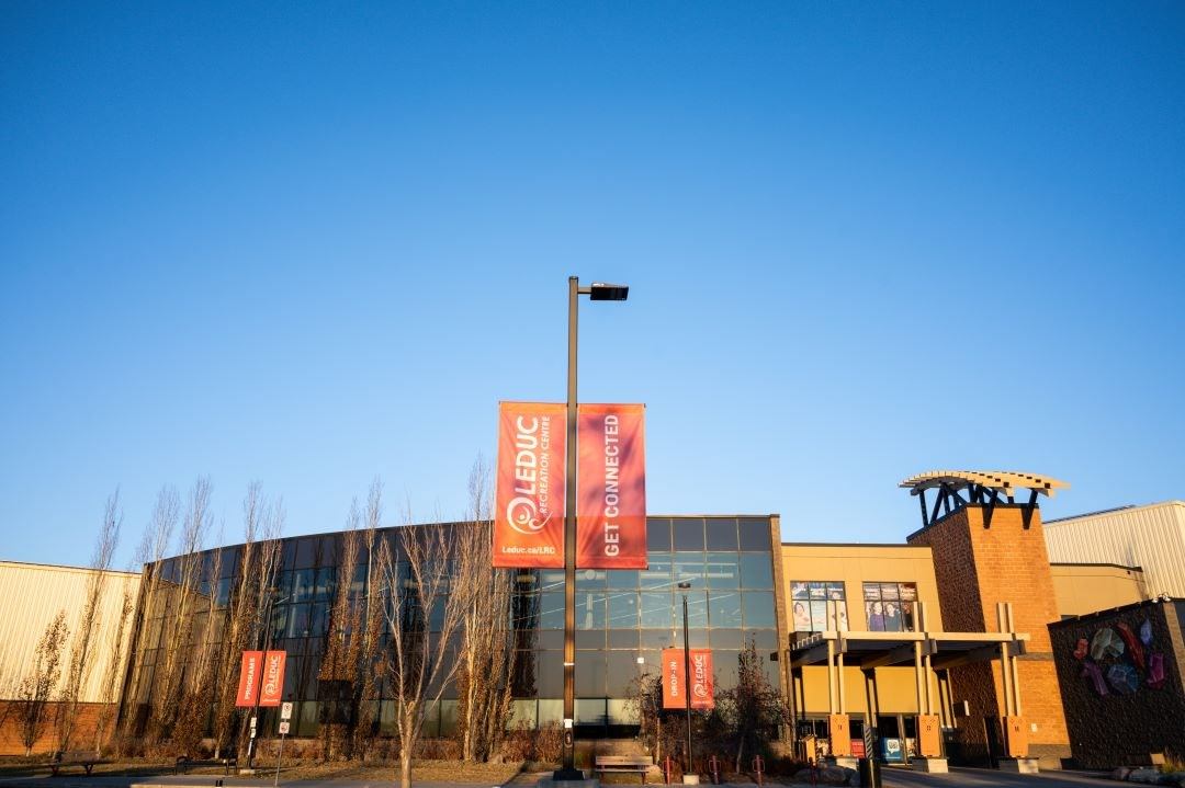 Exterior of Leduc Recreation Centre with glass windows and red banners.