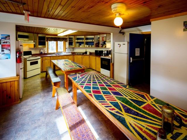 Spacious kitchen and dining room with wood walls, long tables.