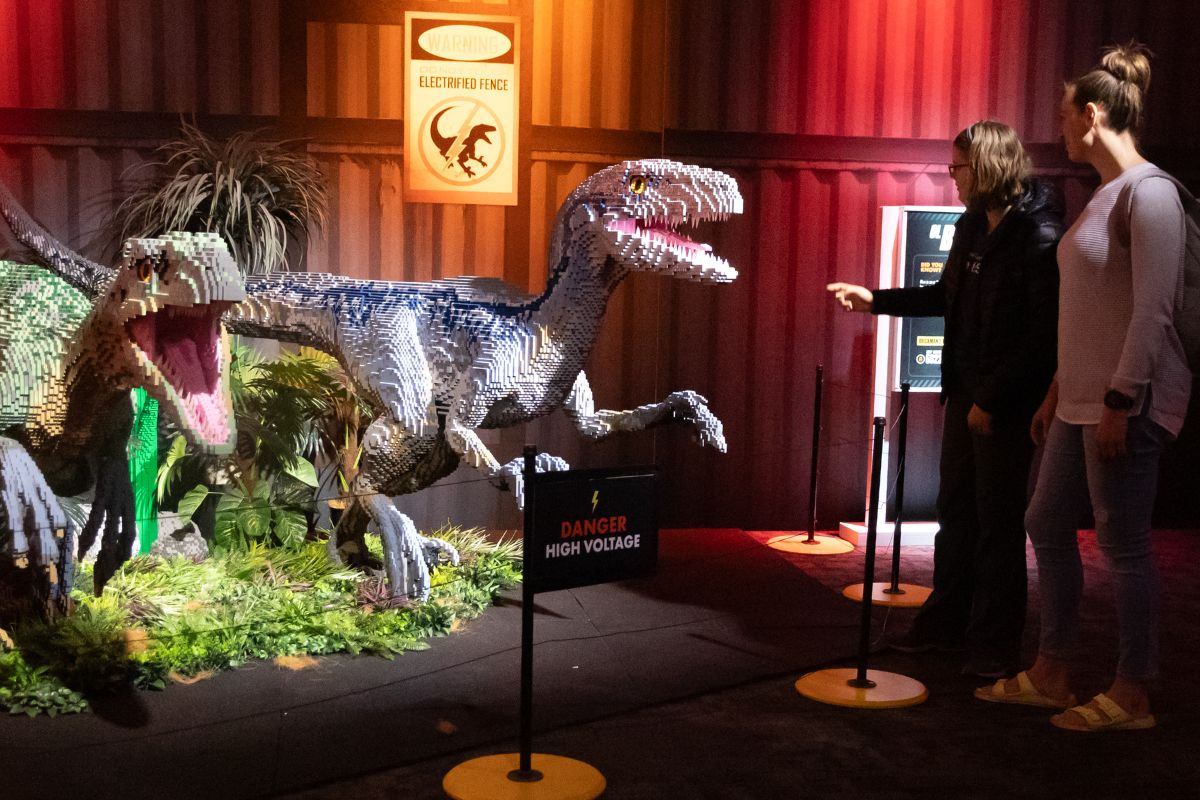 Two LEGO Velociraptors in a dramatic exhibit with visitors and a “Danger” sign.