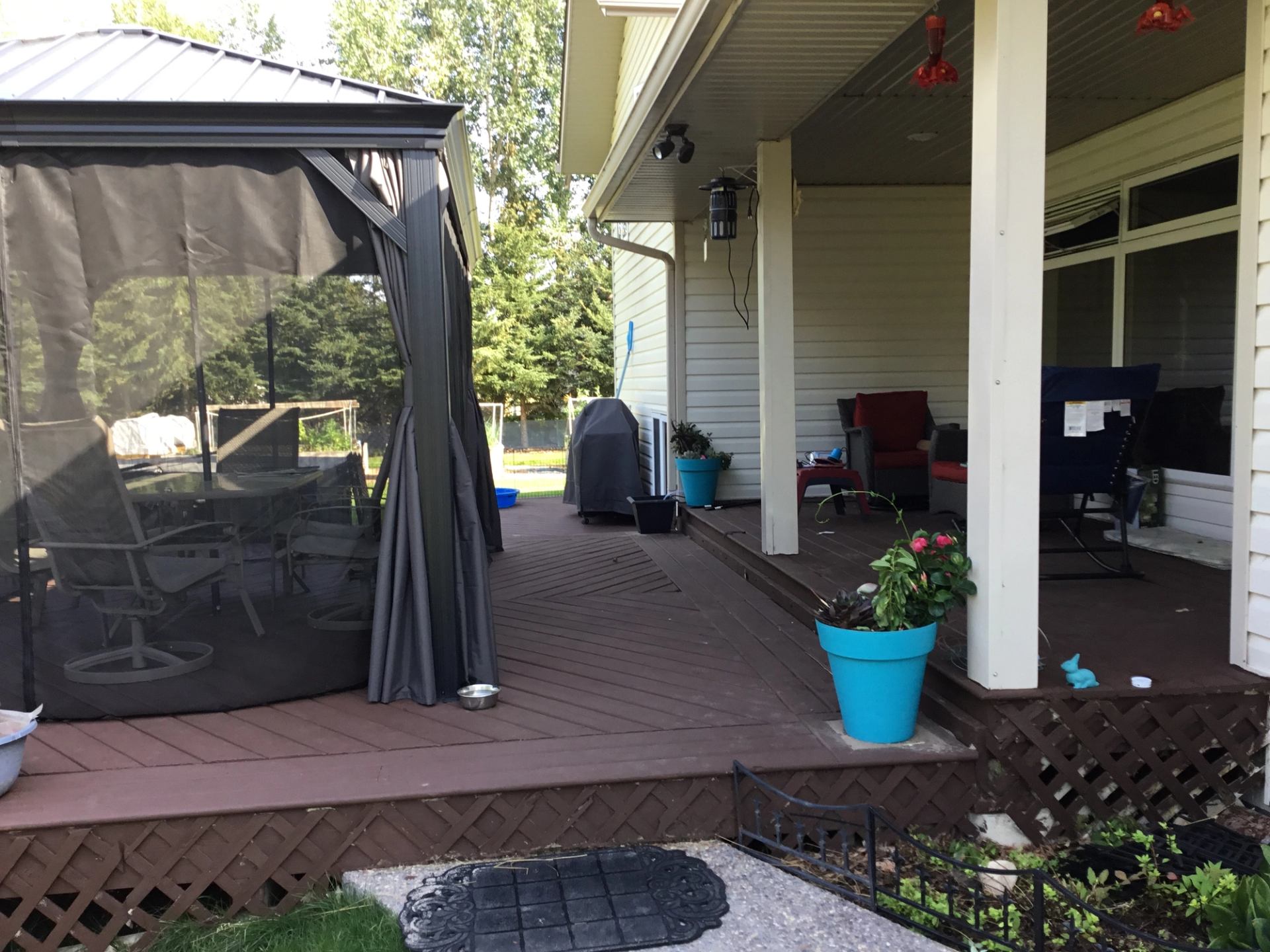 Backyard deck with gazebo, patio furniture, barbecue grill and turquoise planters.