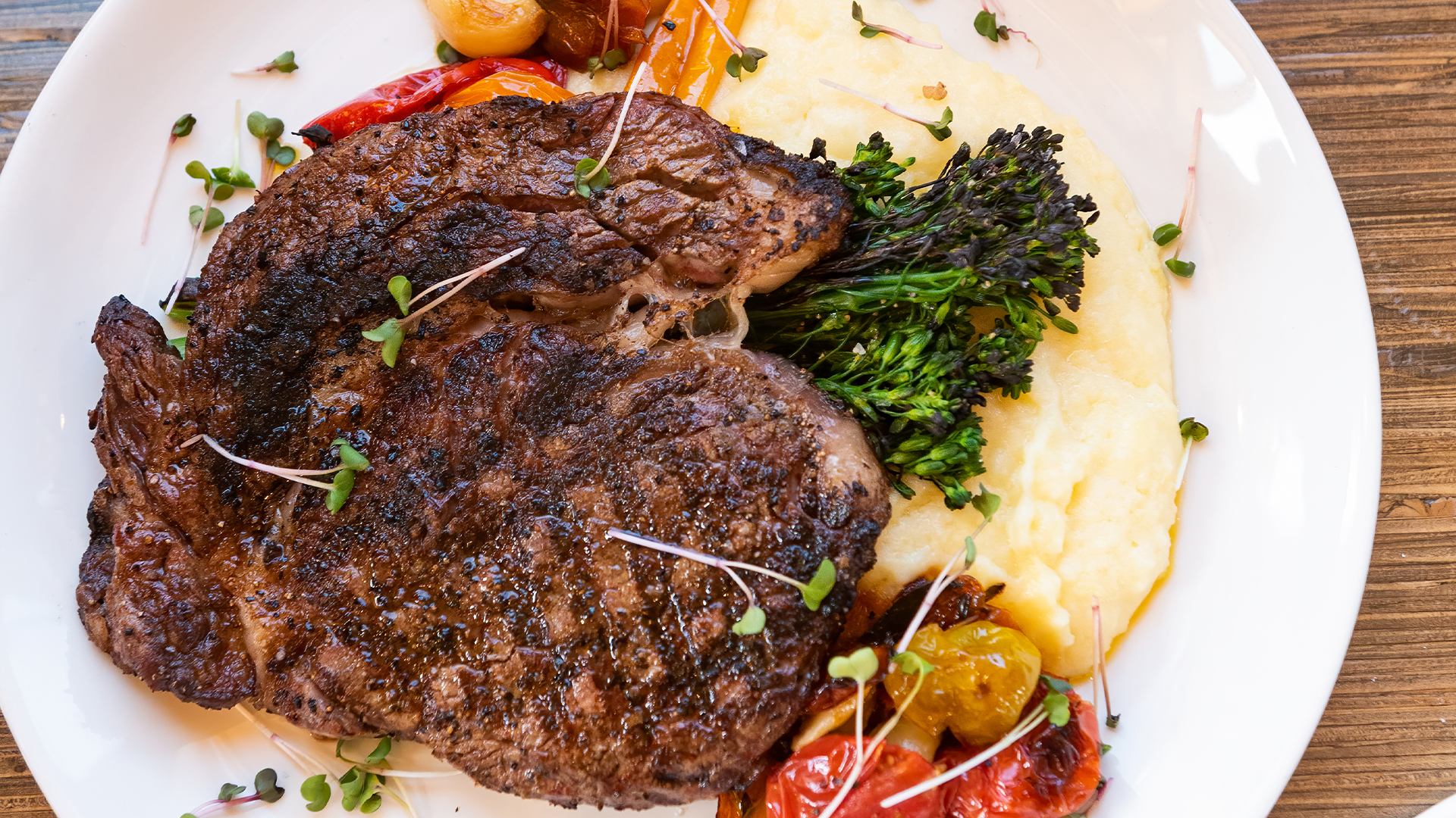 Grilled steak served with mashed potatoes, broccolini, and roasted vegetables at The Grizzly Paw.