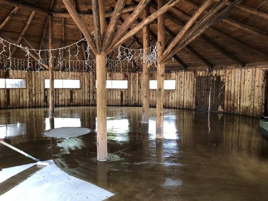 Interior of a wooden log building with poles and lights