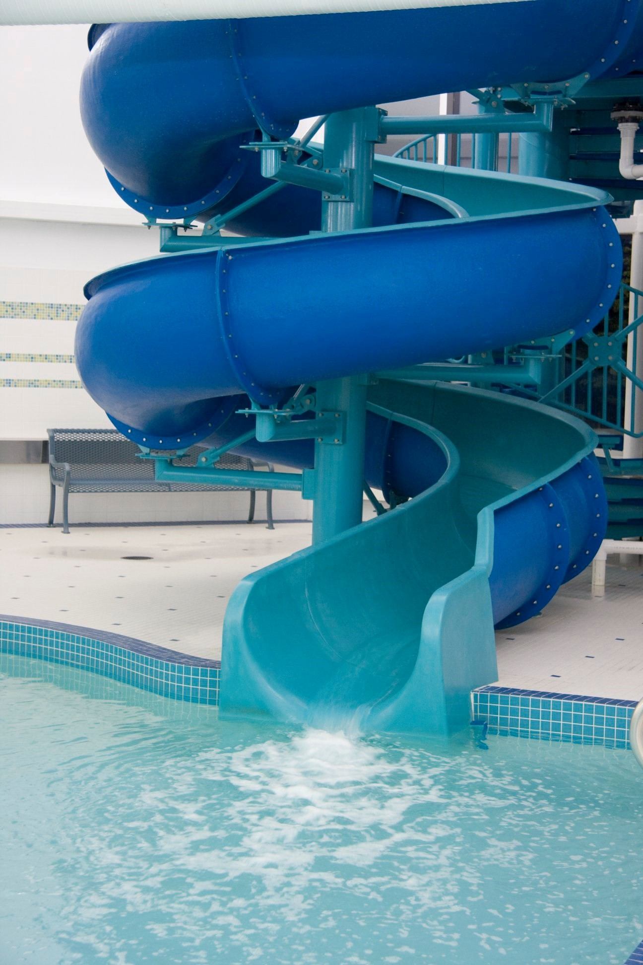 Blue spiral waterslide ending in a clear indoor pool at St. Albert Inn & Suites.