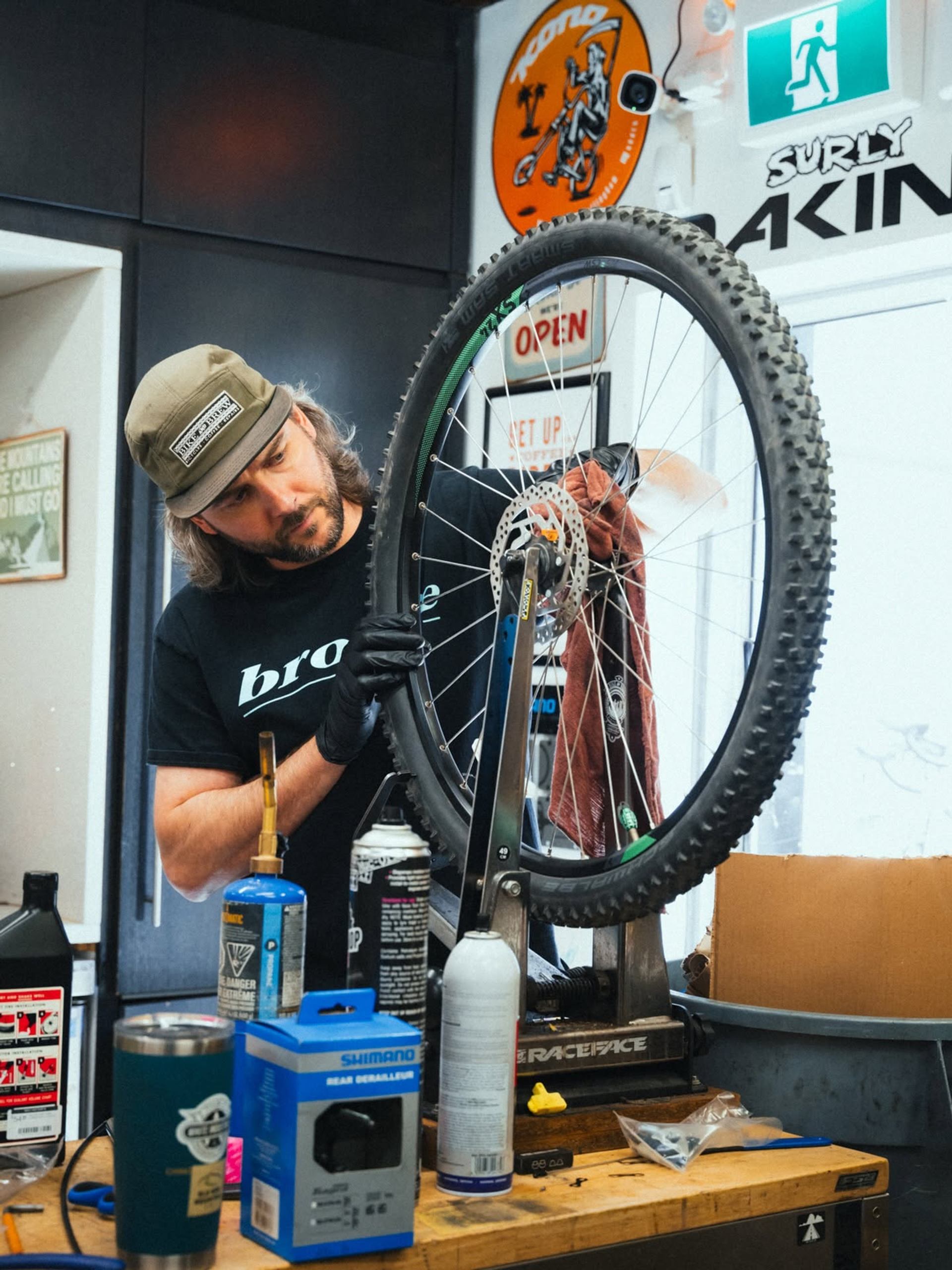 Bicycle mechanic works on a mountain bike wheel mounted in a repair stand.