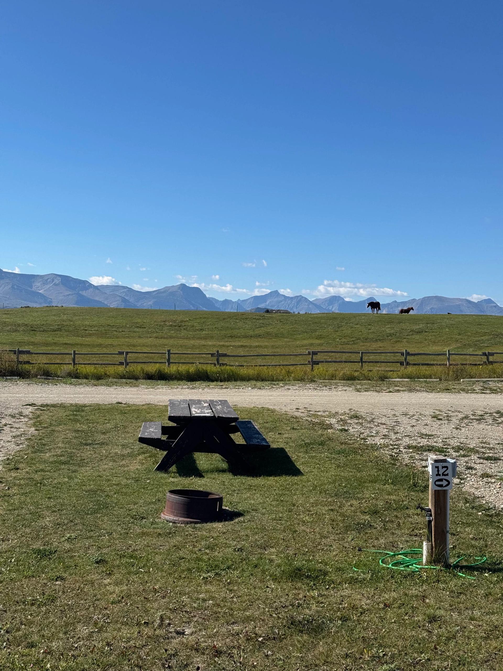 A campsite with a picnic table facing rolling hills and distant mountains.