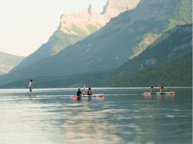 Paddleboarders and boaters on a scenic mountain lake.