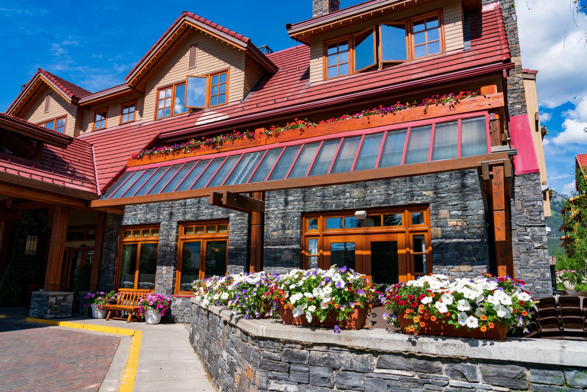 Banff Ptarmigan Inn with flower boxes and red-tiled roof under blue sky.