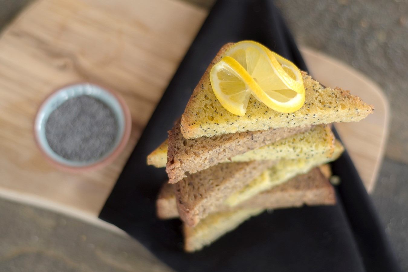 Stacked lemon poppyseed bread slices topped with lemon twists.