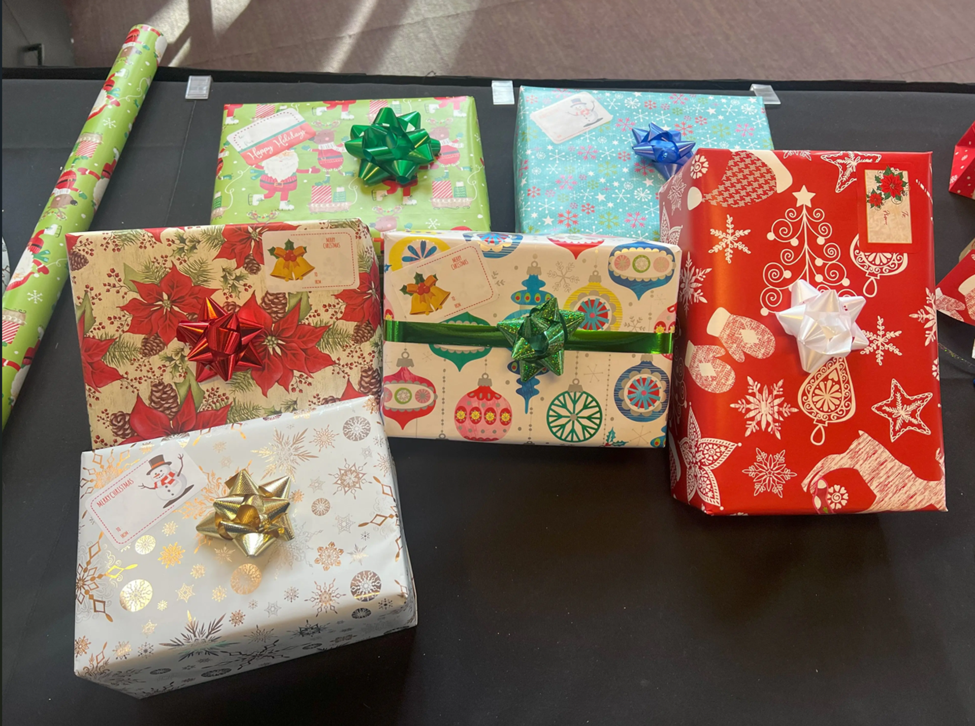 Festively wrapped holiday gifts with colorful bows displayed on a table.