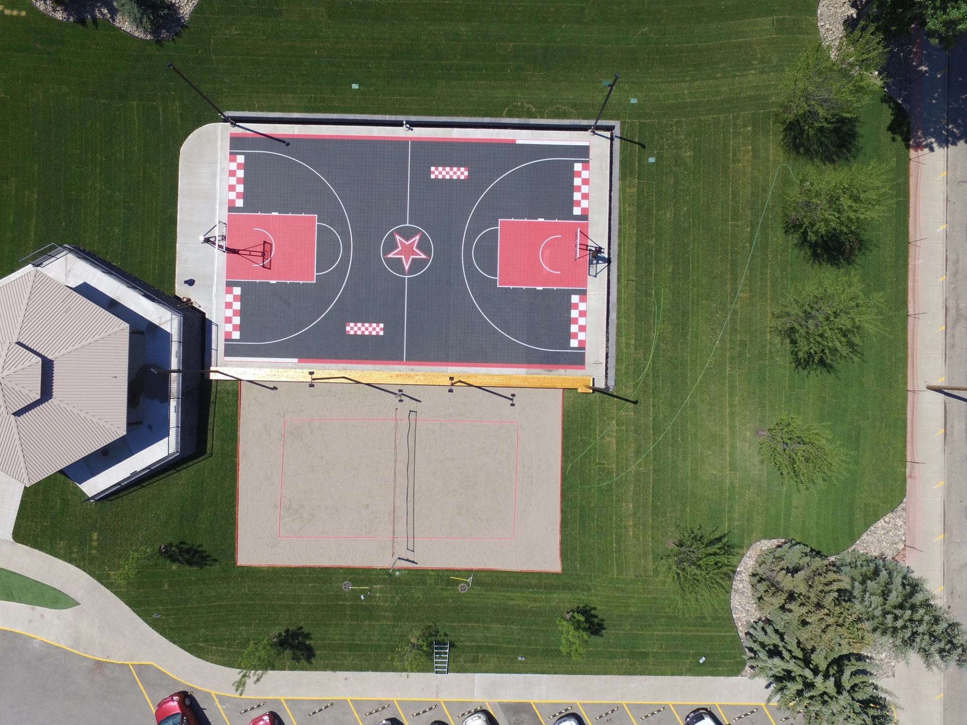 Aerial view of basketball and volleyball courts with bold designs and greenery.